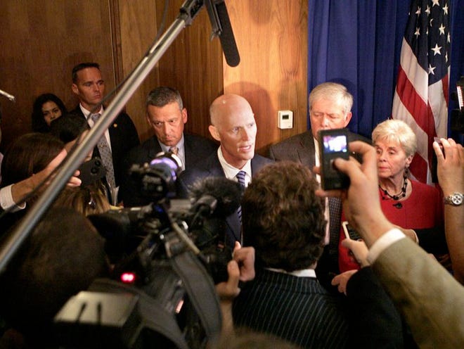 Gov. Rick Scott, center, answers a question as he is surrounded by reporters after signing a bill recently. 
STEVE CANNON | THE ASSOCIATED PRESS