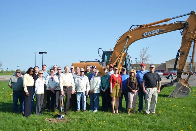 A large group stands on the future site of M1's Greenville West Office with representatives from M1, Wm. Morris & Son, Greenville Area Chamber of Commerce, Builder's Glass, Russell Plumbing & Heating, Nelson Construction, The Service Professor, Baker Painting, Rockford Landscaping and Tree Service, Cobra Drywall, and Simmons Excavating.