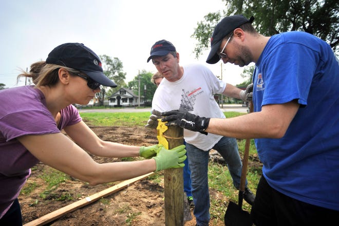 From left, Nadia Burke, Kevin Smith and Dave Lowe of Bosch Garden & Watering use a level to install a wooden post on Sunday during the ground breaking for a new community garden at 1011 S. Western Ave. Bosch Garden & Watering is sponsoring a community garden in the south side of Peoria to support a nonprofit called Gifts in the Moment, which seeks to educate the those in need in Peoria about the importance healthful foods and nutrition.