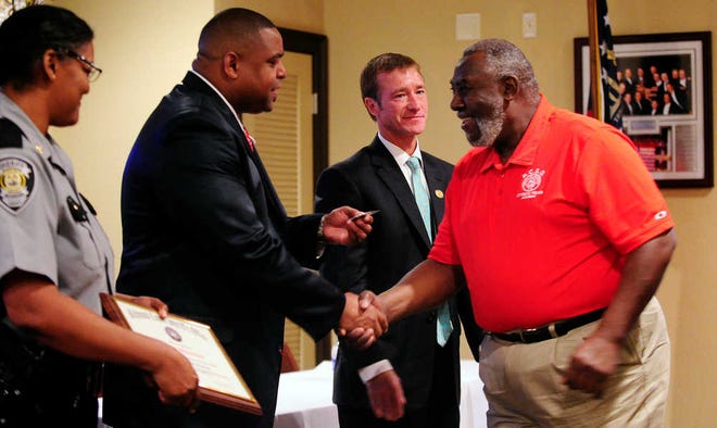 Ernest Muhammad (right) shakes hands with Richmond County Sheriff Richard Roundtree as he goes up to receive his certificate at the Citizen's Police Academy graduation. Mayor Deke Copenhaver (second from right) was the guest speaker.