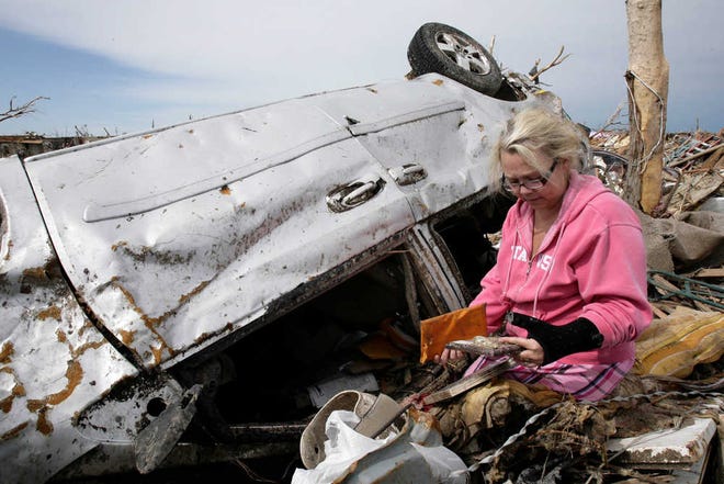 Jacque Burgett looks through the items retrieved from her mother's overturned car in the Westmoor neighborhood of Oklahoma City, Okla. Tuesday, May 21, 2013. A huge tornado roared through the Oklahoma City area Monday, flattening entire neighborhoods and destroying the elementary school with a direct blow as children and teachers huddled against winds. Burgett's mother, Jackie Raper, had loaded the car with valuables hoping to leave the area before the tornado hit, but couldn't get out of the neighborhood. Raper returned to her home only to suffer injury by being buried under the remains of her house. (AP Photo/Tulsa World, Michael Wyke) ONLINE OUT; TV OUT; TULSA OUT