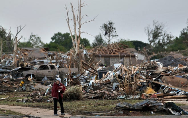 A local resident allowed by security officers into an otherwise sealed off neighborhood walks past the rubble of destroyed homes, one day after a tornado moved through Moore, Okla., Tuesday, May 21, 2013. (AP Photo)