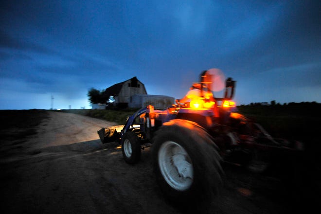 Henry Brockman, after tilling the soil on his vegetable farm in Congerville, drives his tractor back home as it begins to rain Monday evening.