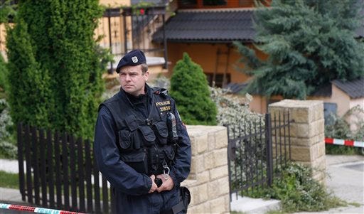 A police man stands guard in front of a crime scene in, Brno, Czech Republic, Thursday, May 23, 2013. An American man suspected of killing four people is on the run in the Czech Republic and likely armed, officials said Thursday.
