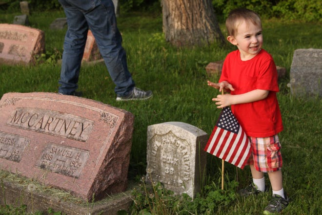 Max Hawk, 4, of Monmouth, puts a flag by the grave of a U.S. soldier buried in Monmouth Cemetery. Max helped his brother, Dakota, 6, decorate the graves of fallen soldiers and veterans in honor of Memorial Day, along with Dakota's Cub Scout Pack 352 and other area Boy Scouts.