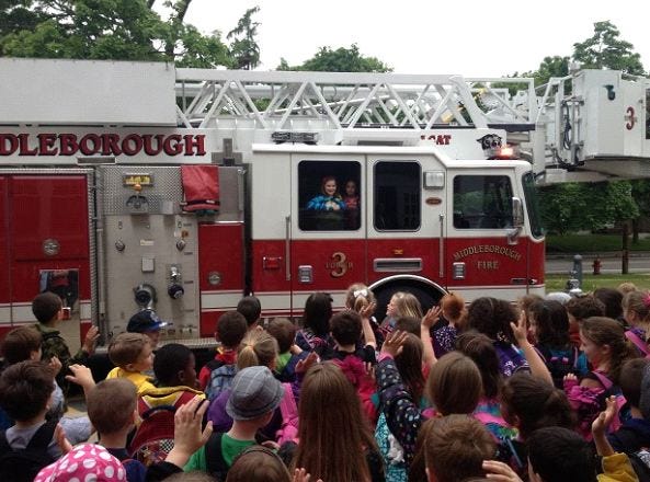 Classmates greet Middleboro girls who arrived to school on a fire truck on Wednesday, May 22, 2013.