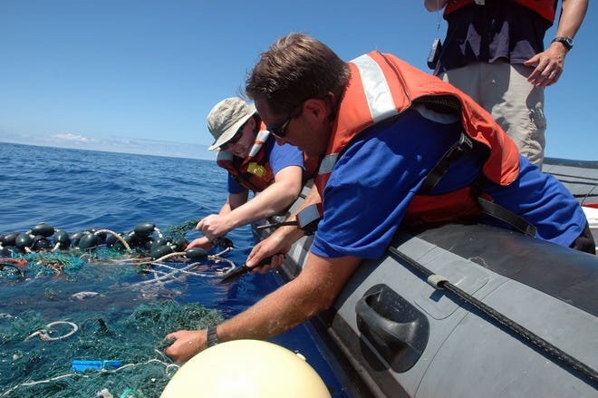 In this Aug. 11, 2009 file photo provided by the Scripps Institution of Oceanography shows Matt Durham, center, pulling in a large patch of sea garbage with the help of Miriam Goldstein, right, in the Pacific Ocean. Plastics discarded by people often end up in the ocean, creating coastal pollution that harms marine life and gathers out at sea in what's become known as the great Pacific garbage patch. Now, California state lawmakers have introduced a law that if passed would require makers of plastic bottles, bags and packaging to replace plastics with more environmentally friendly alternatives. (AP Photo/ Scripps Institution of Oceanography, Mario Aguilera, File)