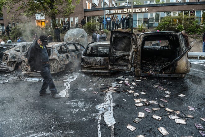 A passerby checks out burned cars in the Stockholm suburb of Rinkeby.THE ASSOCIATED PRESS