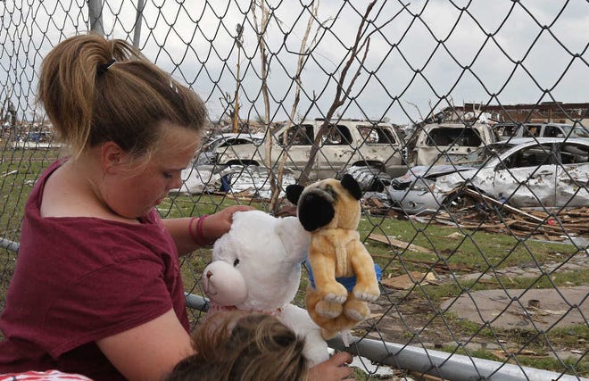 Ashlyn Kelley, 11, who is in the fifth grade and was in the Plaza Towers elementary school when the tornado hit Moore, Okla., ties stuffed animals to the perimeter fence as a memorial to the seven students who died at the school.