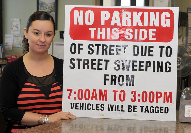 Traffic clerk Stephanie MacArthur holds up a no-parking sign that is placed in neighborhoods 24 hours before street cleaning begins.