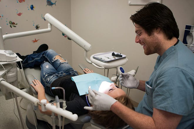 Knox County Health Department dentist Dr. Matt Rozny examines the teeth of Bry Martin in November 2012. The state of Illinois still owes the Health Department payments since September 2012.