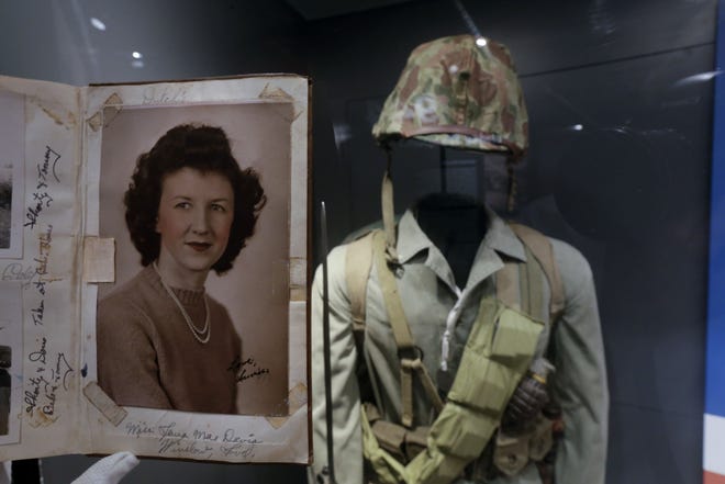 In this May 23, 2013 photo, a page of out of the diary of 22-year-old Marine Cpl. Thomas Jones featuring a photo of his high school sweetheart, Laura Mae Davis Burlingame, is on display at the National WWII Museum in New Orleans. Behind is a Marine uniform like one Jones, who died in the bloody assault on a Japanese-held island during World War II, would have worn. Before Jones died, he wrote what he called his "last life request" to anyone who might find his diary: Please give it to Laura Mae Davis, the girl he loved. Laura Mae Davis Burlingame - she married an Army Air Corps man in 1945 - had given the diary to Jones, and didn't know it had survived him until visiting the museum on April 24. (AP Photo/Gerald Herbert)