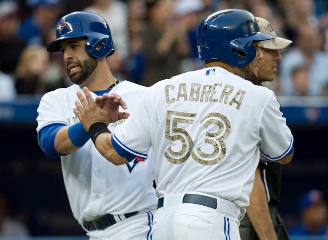 Toronto's Jose Bautista, left, celebrates a run with teammate Melky Cabrera, right, during third inning Monday in Toronto.