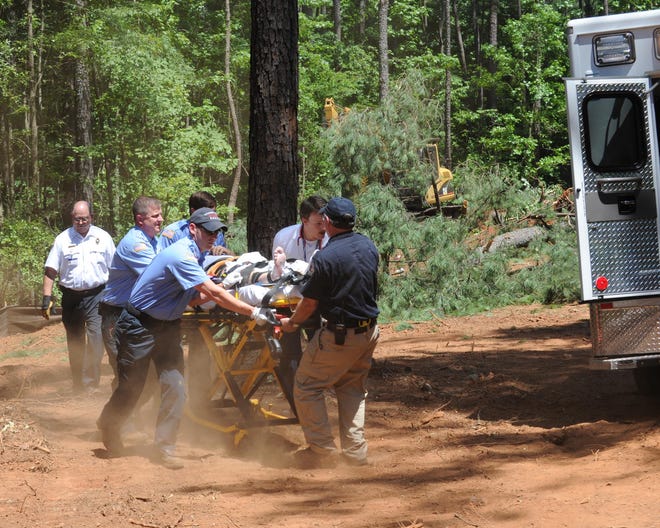 Emergency personnel rush Brent Watkins, owner of Brent Watkins Enterprises, to an ambulance after being injured by tree that fell on him as he and a coworker were clearing a lot on Mullikan Road.