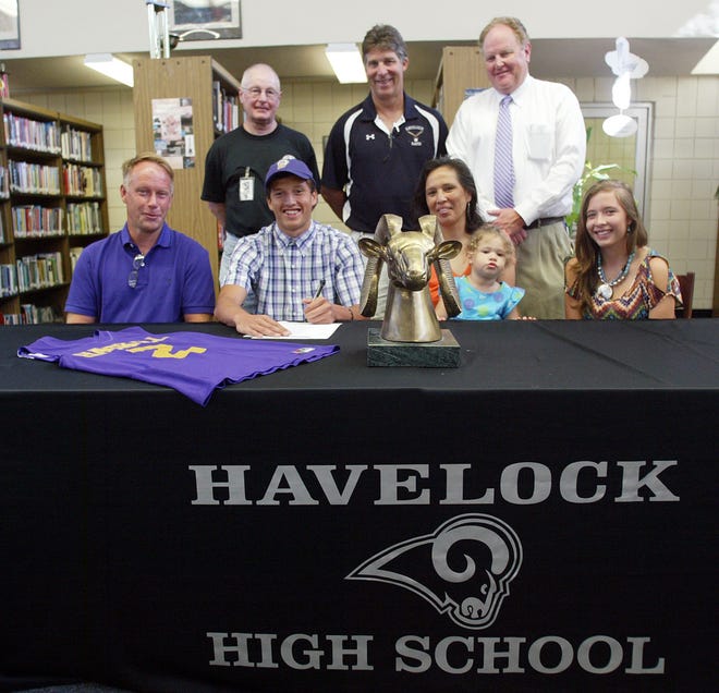 Surrounded by family, coaches and school administrators, Zack Bruns, seated second from left, signs to play college basketball at Haskell University in Kansas.
