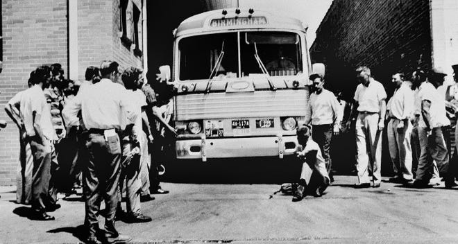 One unidentified white man sits in front of Greyhound bus to prevent it from leaving the station with load of Freedom Riders testing bus station segregation in South, Sunday, May 15, 1961, Anniston, Alabama. Other white men mill around bus station. The bus was stopped by a flat tire and surrounded by a white crowd outside Anniston, and burned a short time later. The passengers got off without serious injury. (AP Photo)