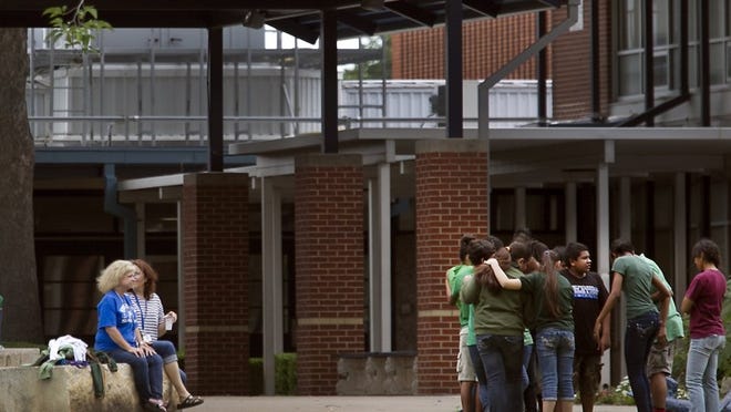 Burnet Middle School students huddle in front of the school after being evacuated because of what officials said appeared to be an unfinished acid bomb. Five students and three staff members were treated Friday afternoon.