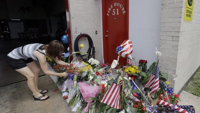 Shannon Neira places flowers at a makeshift memorial at Houston Fire Station 51 on Saturday. Four firefighters searching for people they thought might be trapped in a blazing Houston motel and restaurant Friday were killed when part of the structure collapsed and ensnared them, authorities said. (AP Photo/David J. Phillip)