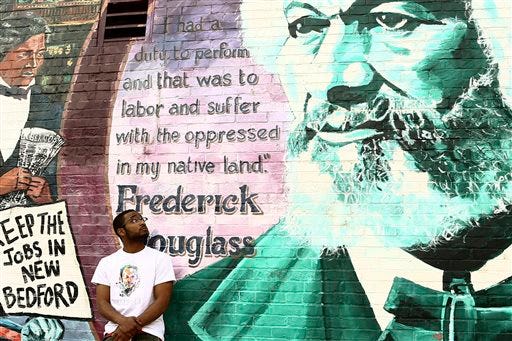 In this May 10, 2013 photo, Abdourahmane Doumbouya, lower left, poses at a mural in downtown New Bedford, Mass. Doumbouya, a native of Senegal, was raised in New Bedford and recently moved to Boston to pursue his career as a rapper.