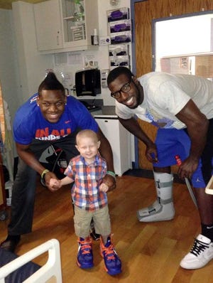 Provided by Amber Clements Florida basketball players Patric Young (right) and Will Yeguete have formed a special bond with 3-year-old leukemia patient Kaedyn Ballew. Kaedyn is wearing game shoes Yeguete gave him.