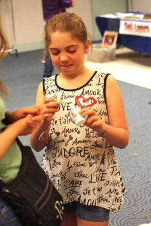 Grace Unruh, 9, of Topeka, prepares to eat a Larvet snack at Saturday's "Dig Into Reading" kickoff event at the Topeka and Shawnee County Public Library, 1515 S.W. 10th. Made of beetle larvae, Grace's snack was flavored with Mexican spice. She ate it and said it tasted good.