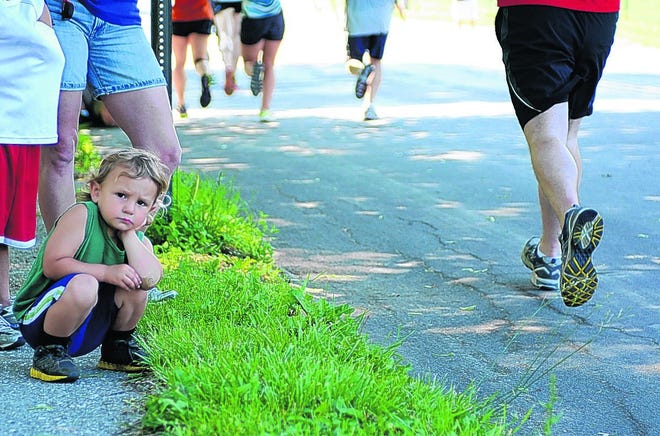 Three-year-old Vincent Russo watches as runners pass by on their way down Wisner Avenue.