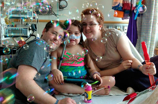 FILE - In this May 30, 2013 file photo provided by the Murnaghan family, Sarah Murnaghan, center, celebrates the 100th day of her stay in Children's Hospital of Philadelphia with her father, Fran, left, and mother, Janet. A federal judge in Philadelphia on Wednesday, June 5, 2013 made the dying 10-year-old eligible to seek donor lungs from an adult transplant list. (AP Photo/Murnaghan Family, File)