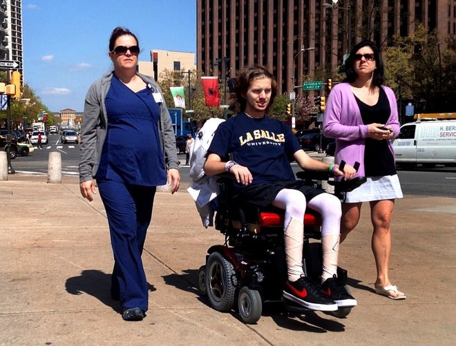 Matt Cruz, 16, his mother Megan, and a physical rehabilitation nurse walk to LOVE Park in Philadelphia on Friday April 26, 2013. Matt was critically injured in a tour bus crash returning form Boston on Feb. 2. The walk to the park was the first time he was outdoors since the crash.