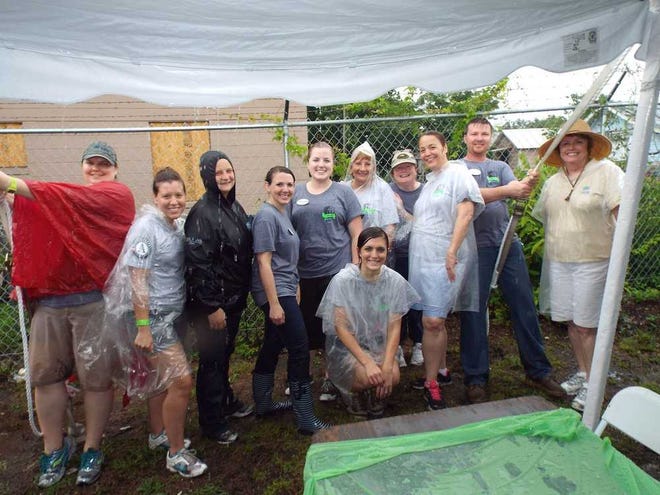 Wet staffers of Habitat for Humanity of Jacksonville gather under the lunch tent at the nonprofit's 25-house build on Thursday. Despite inclement weather, they and a group of volunteers worked on the houses Thursday morning.