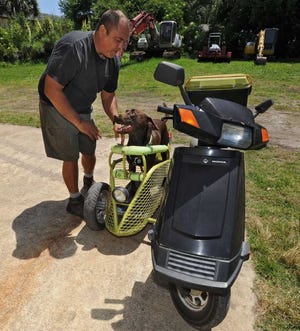 Bob.Mack@jacksonville.com --5/30/13 -- Dave Nissen hooks Spany's collar to the protective rail of the sidecar before a ride. Nissen of Atlantic Beach has a doggie sidecar he custom-built for his Honda scooter and his chocolate lab, Spanky. They've logged over 9.000 miles together. On Thursday May 30, 2013 Nissen and Spanky cruised to the fabrication shop Dave operates just off Mayport Road and then rode to Dutton Island Preserve with Spanky in his sidecar.  (The Florida Times-Union, Bob Mack)