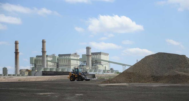 A front loader drives toward a pile of coal ash Thursday at Xcel Energy's Harrington Station. The ash, a byproduct produced at the station, contains small amounts of toxic chemicals and is sold for industrial uses, such as road construction.