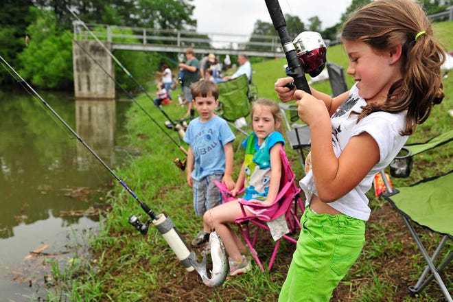Kamryn Parrish reels in one of four catfish she caught before 10 a.m. as her cousins Troy and Lillie watch during the Breakfast Optimist Club's Kids Fishing Rodeo at Augusta Technical College's catfish pond.