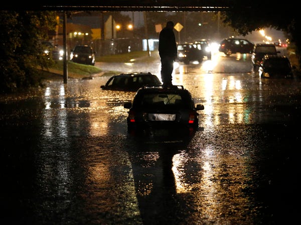 FILE - In this Friday, May 31, 2013, file photo, a man stands on top of his car as it is flooded on S. May Avenue near SW 25th in Oklahoma City. For decades, weather researchers have worked to give people as much warning as possible before a tornado or hurricane hits so that residents have time to protect themselves from nature's sometimes violent fury. But experts acknowledge there is some debate over whether increasing lead time is always a good thing (AP Photo/The Oklahoman, Sarah Phipps)