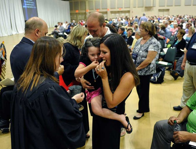 Mary Crider, center, and holds her daughter Sara Crider while they both take communion during the opening worship service at the North Georgia Conference of The United Methodist Church at the Classic Center in Athens, Ga., Tuesday, June 11, 2013. (AJ Reynolds/Staff)