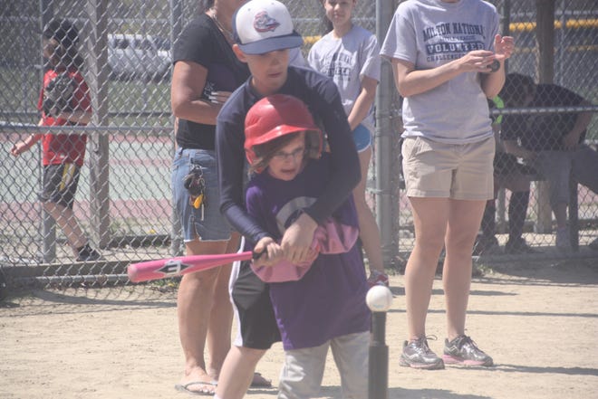 Rich Laine helps Challenger Division player Francesca Vitti swing the bat.