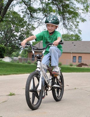 Christopher D. Corrigan, 9, rides his bicycle around his subdivision. Corrigan and his brother are among the youngsters who will attend a bike safety program Friday at the Pontiac Extension office.
