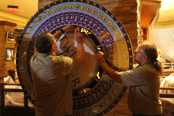 Carpenter Tom Covill, right, of West Greenwich, and Greg Fox, of Lincoln, install a spinning wheel game on the gambling floor at Twin River in Lincoln last month ahead of the opening of casino table gaming, which is scheduled to begin later this month.