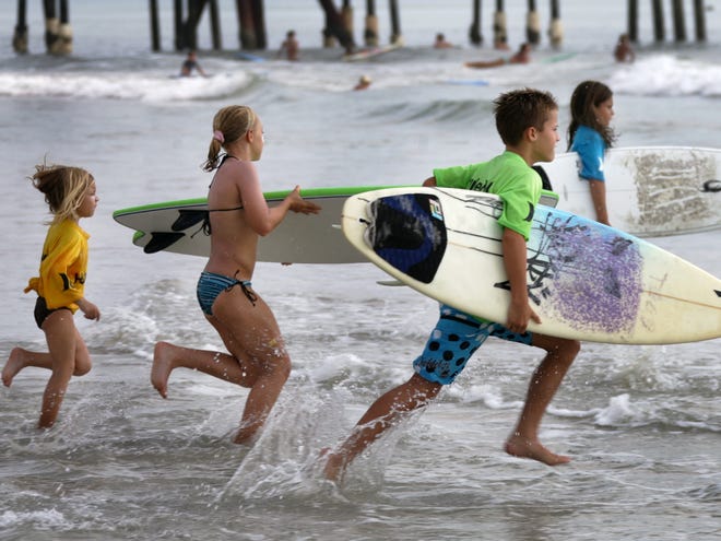 Young surfers charge into the surf on June 20, 2011, for their first heat in the Hurley " Rip My Shred Stick " surfing event on Daytona Beach near the pier.