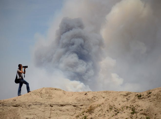 A photographer takes photos of the Black Forest Fire as it burns out of control for a second straight day near Colorado Springs, Colo. on Wednesday, June 12, 2013. Three Colorado wildfires fueled by hot temperatures, gusty winds and thick, bone-dry forests have together burned dozens of homes and led to the evacuation of more than 7,000 residents and nearly 1,000 inmates at medium-security prison. (AP Photo/Bryan Oller)