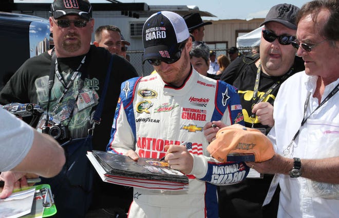 Driver Dale Earnhardt Jr., signs autographs for fans before a practice session for Sunday's NASCAR Sprint Cup series auto race at Michigan International Speedway Friday, June 14, 2013, in Brooklyn, Mich. (AP Photo/Bob Brodbeck)