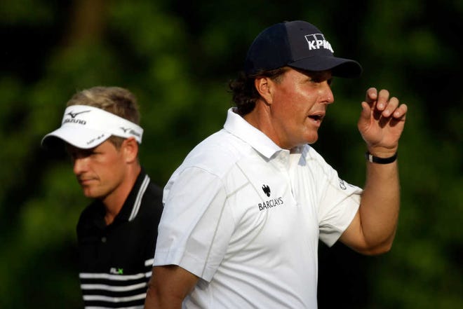 Phil Mickelson, right, reacts after putting on the 12th green with Luke Donald, of England, during the third round of the U.S. Open golf tournament at Merion Golf Club, Saturday, June 15, 2013, in Ardmore, Pa. (AP Photo/Morry Gash)