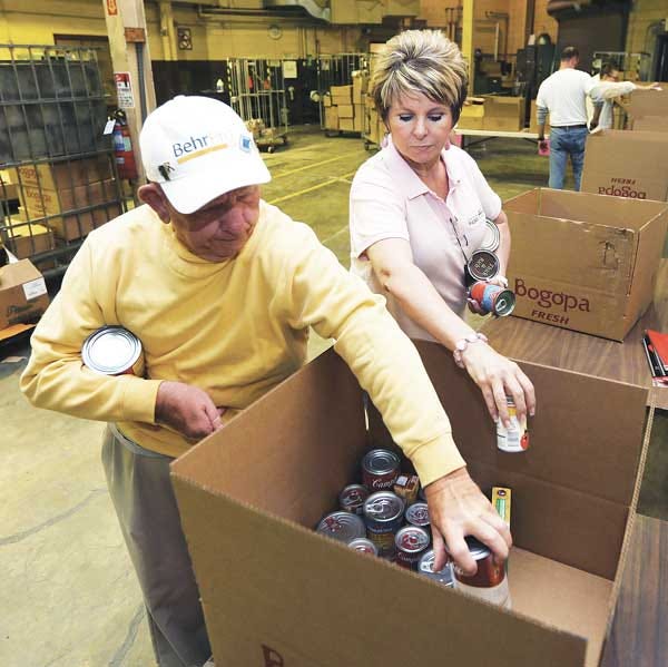 Photo by Tracy Klimek/New Jersey Herald - Pass It Along program director Kelly Bonventre and volunteer Bob Taylor place donated canned items into a box to deliver to local pantries.