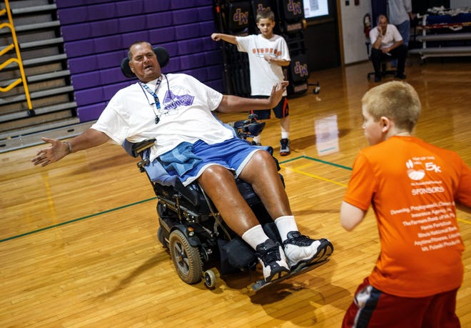 Bill Rucks plays the part of a defender as young basketball players run an offensive ball passing drill during a summer basketball camp at Mt. Pulaski High School, Friday, June 7, 2013, in Mt. Pulaski, Ill. Rucks, a former coach himself at Mt. Pulaski, will be returning to the sidelines as an assistant coach for boys basketball coach Ryan Diebert even though medical issues have confined him to a wheelchair.