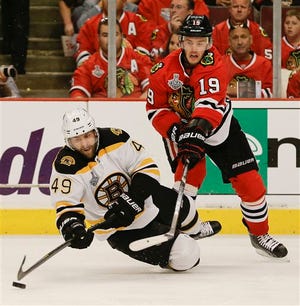 Boston Bruins center Rich Peverley (49) falls to the ice as he keeps the puck from Chicago Blackhawks center Jonathan Toews (19) in the second period during Game 2 of the NHL hockey Stanley Cup Finals, Saturday, June 15, 2013, in Chicago.