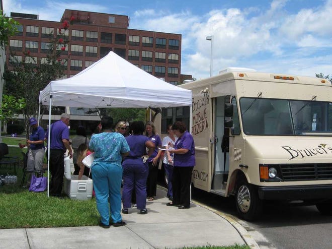 Dozens of certified nursing assistants line up outside the Brucci's mobile pizzeria in the driveway between the St. Catherine Labouré Manor and St. Vincent's Medical Center Riverside during Community Hospice's Great Food Truck Round-Up to celebrate Nursing Assistants Week.