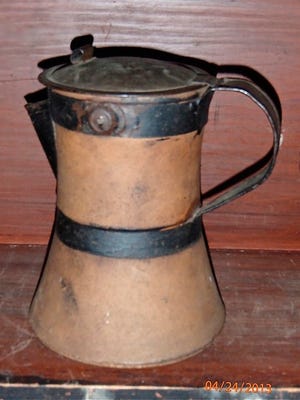 This stoneware jar has been made into a pitcher by adding metal bands, spout, lid and handle. Our ancestors believed in the adage “waste not, want not.”