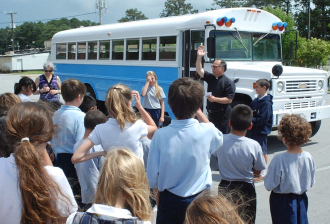 Father Greg Spencer blesses the Annunciation Catholic School's new bus.
