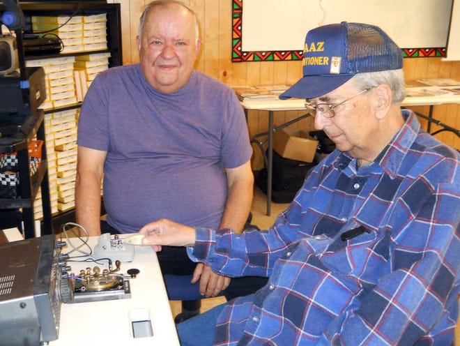 Above: Bob Norman watches as his friend Clarence Cerrous tap out a message in Morse code. Cerrous has been a ham radio operator for 55 years.  Left: Operator Joe Bassette (yellow shirt) works the radio as other club members perform other duties.
