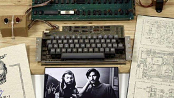 This undated photo provided by Christie’s Auction House shows an “Apple 1” prototype computer, built in 1976, accompanied by an operation manual and schematic as well as a photo of its inventors, Steve Wozniak, left, and Steve Jobs. One of the very first Apple 1 computers, it goes on sale later this month at Christie's auction house, the latest in a recent run of vintage tech sales that have attracted some eye-popping prices.