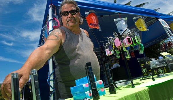 Mike Liddon arranges solar-powered flashlights June 14 at his Solar-Shack tent at The Market at San Joaquin Delta College in Stockton. He lost his job in the recession and came up with the business of selling solar-powered gadgets and kits out of thin air.
